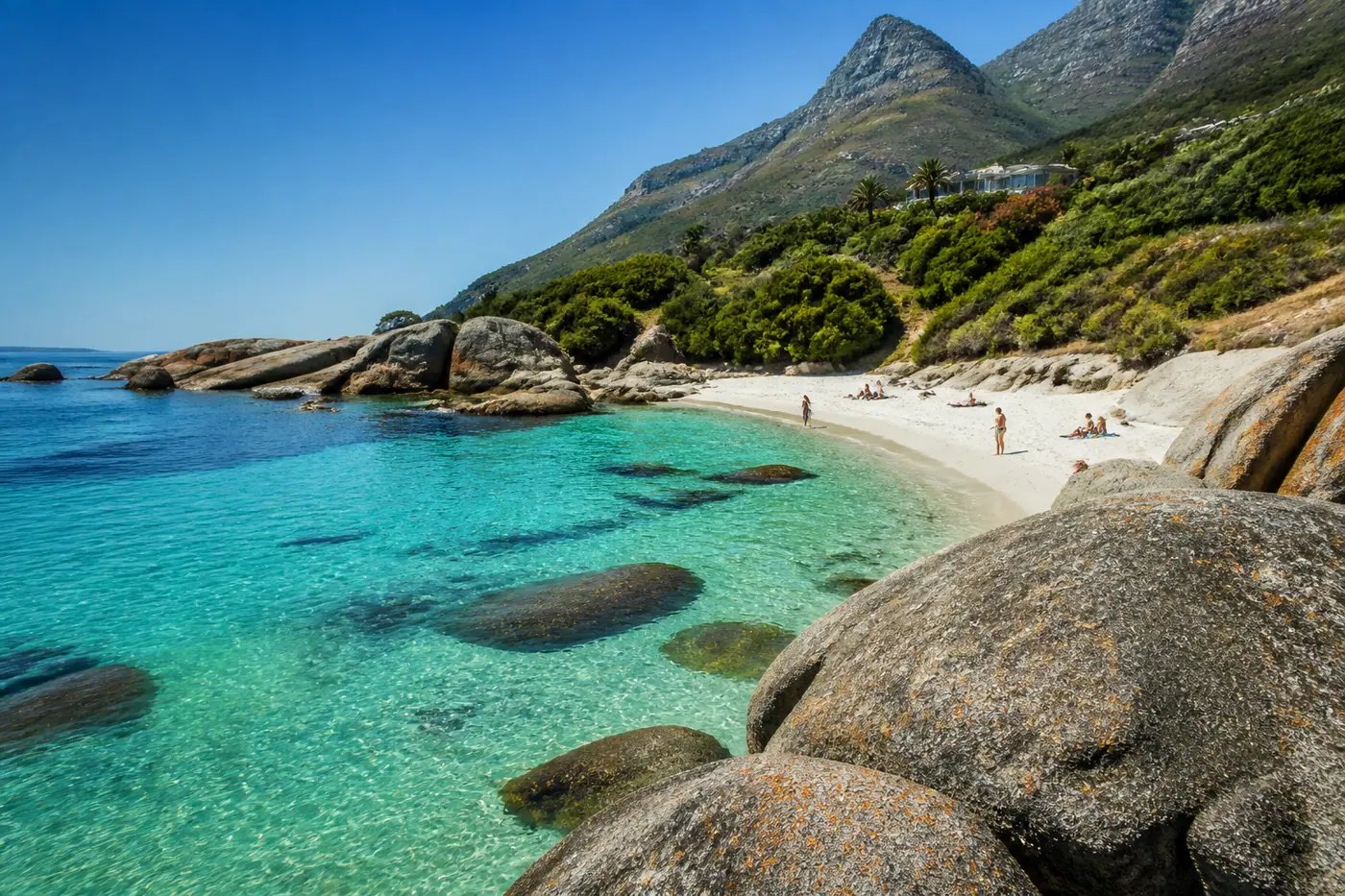 Camps Bay cove with turquoise water, granite boulders and the Twelve Apostles